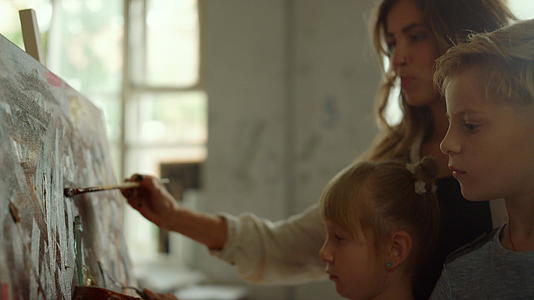 女教师和儿童在室内绘画视频的预览图