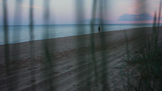 在寒冷的早晨剪影女子在黄昏漫步沙滩视频的预览图