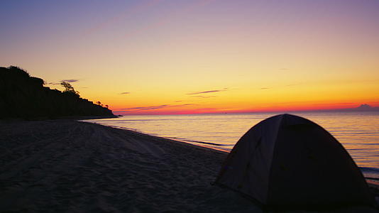 早晨金色的日出在黑暗的沙滩上露营帐篷视频的预览图