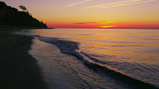 美丽的岩石海滨景色反对明亮的橙色日落视频的预览图