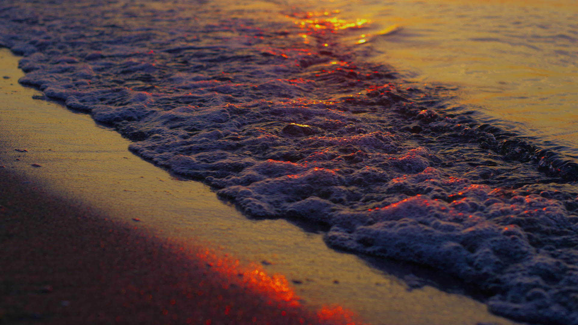 特写镜头海浪在慢动作的夜晚橙色日落飞溅的沙滩视频的预览图