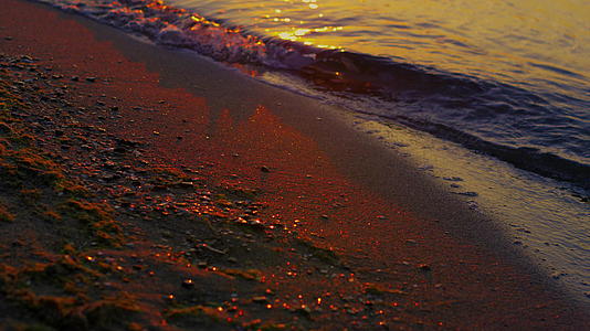 特写镜头湖的波浪在早晨日出黎明的沙岸边飞溅视频的预览图