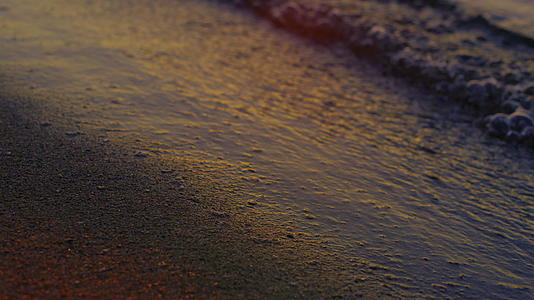 特写平静的海浪在黄昏时分反射出明亮的金色日落视频的预览图