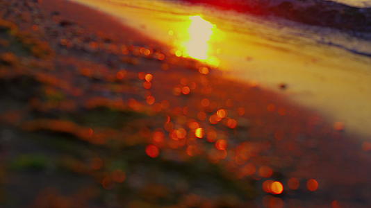 夕阳傍晚海浪中的太阳光反射着金色的沙滩视频的预览图
