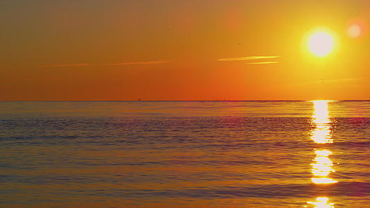 在清澈的蓝色海水中橙色的太阳平静地看着日落视频的预览图
