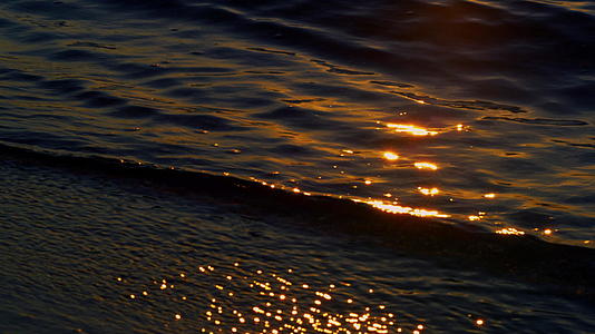 日落时分黑暗的海水打破了沙滩视频的预览图