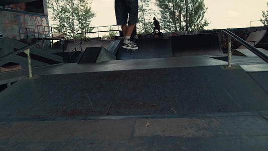 极端男孩骑着滑板车在城市滑板公园的坡道上跳跃视频的预览图