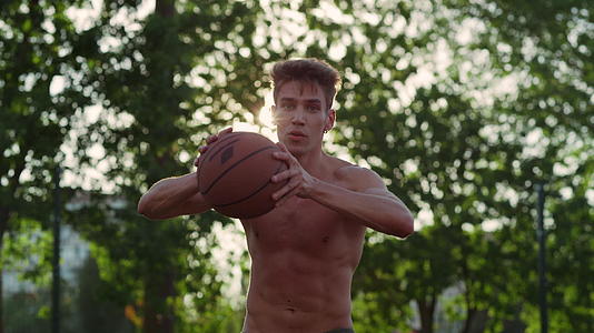 肌肉发达的运动员在运动场上练习街头篮球视频的预览图