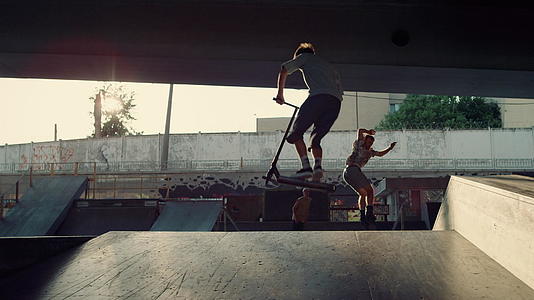在城市明亮的阳光滑板公园里青少年运动员一起表演特技视频的预览图