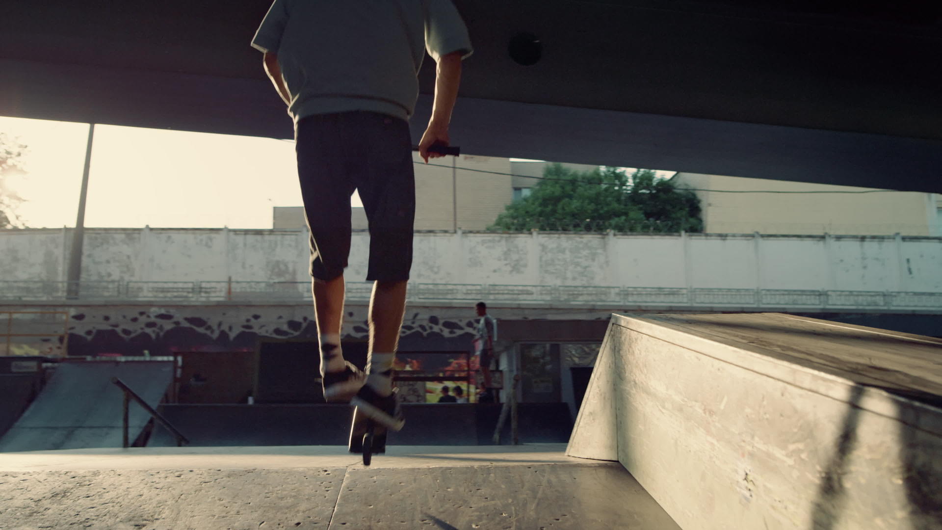 运动型男性在城市滑板公园骑滑板车和越野自行车玩花样视频的预览图