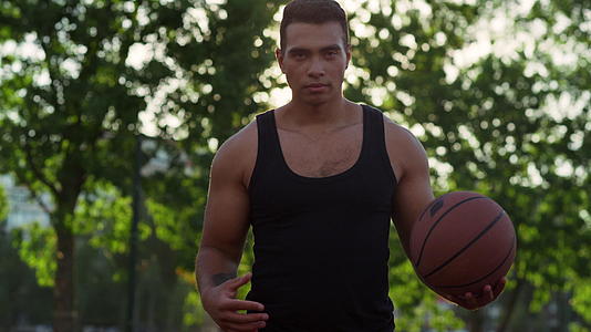 专注的混血运动员在操场上独自练习篮球视频的预览图