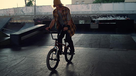 运动型男性骑越野自行车在滑板公园做危险把戏视频的预览图