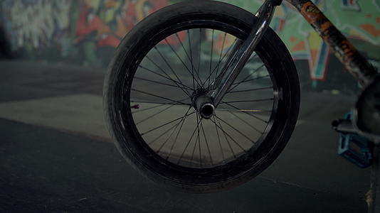 在涂鸦墙滑板公园旋转的越野自行车车轮视频的预览图