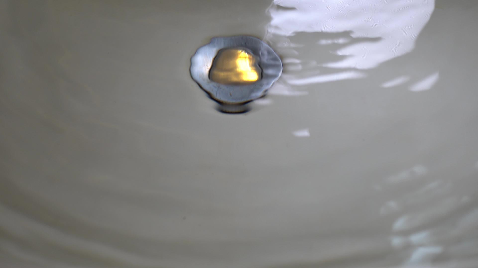 关闭马桶里的水龙头和洗手盆水滴慢慢落在水面上水面反射视频的预览图