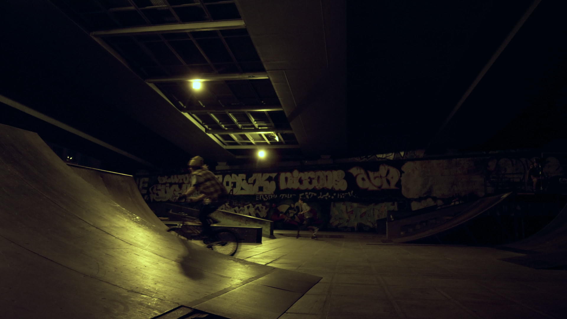 青少年bmx骑手在夜间滑板公园的坡道上骑自行车视频的预览图