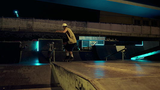 极端的朋友在夜间滑板公园的轨道上表演跳跃特技视频的预览图