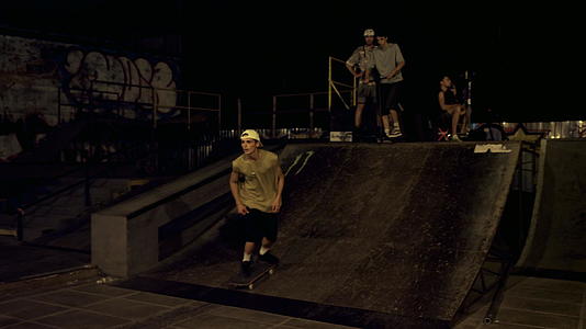 夜间滑板公园有涂鸦墙的坡道上年轻人跳上坡道视频的预览图
