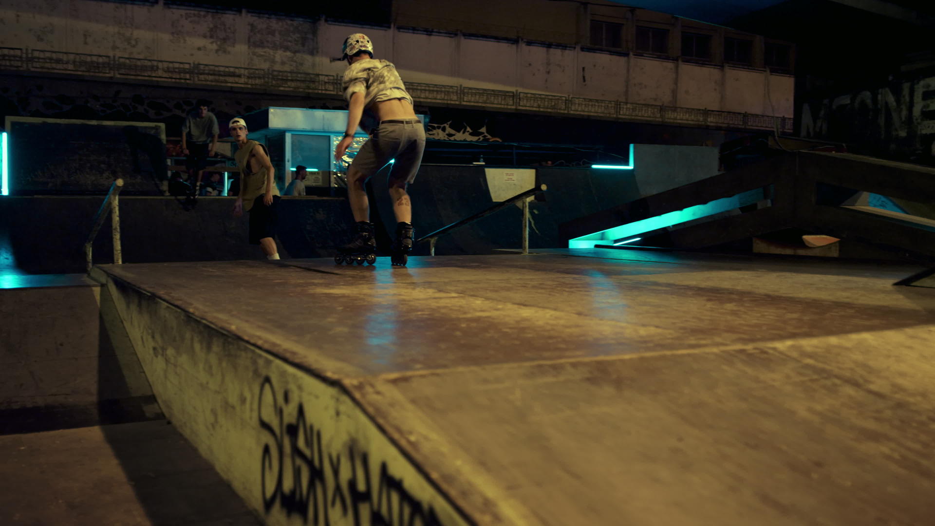 在夜间滑板公园的斜坡上活跃嬉皮士表演跳跃技巧和涂鸦视频的预览图