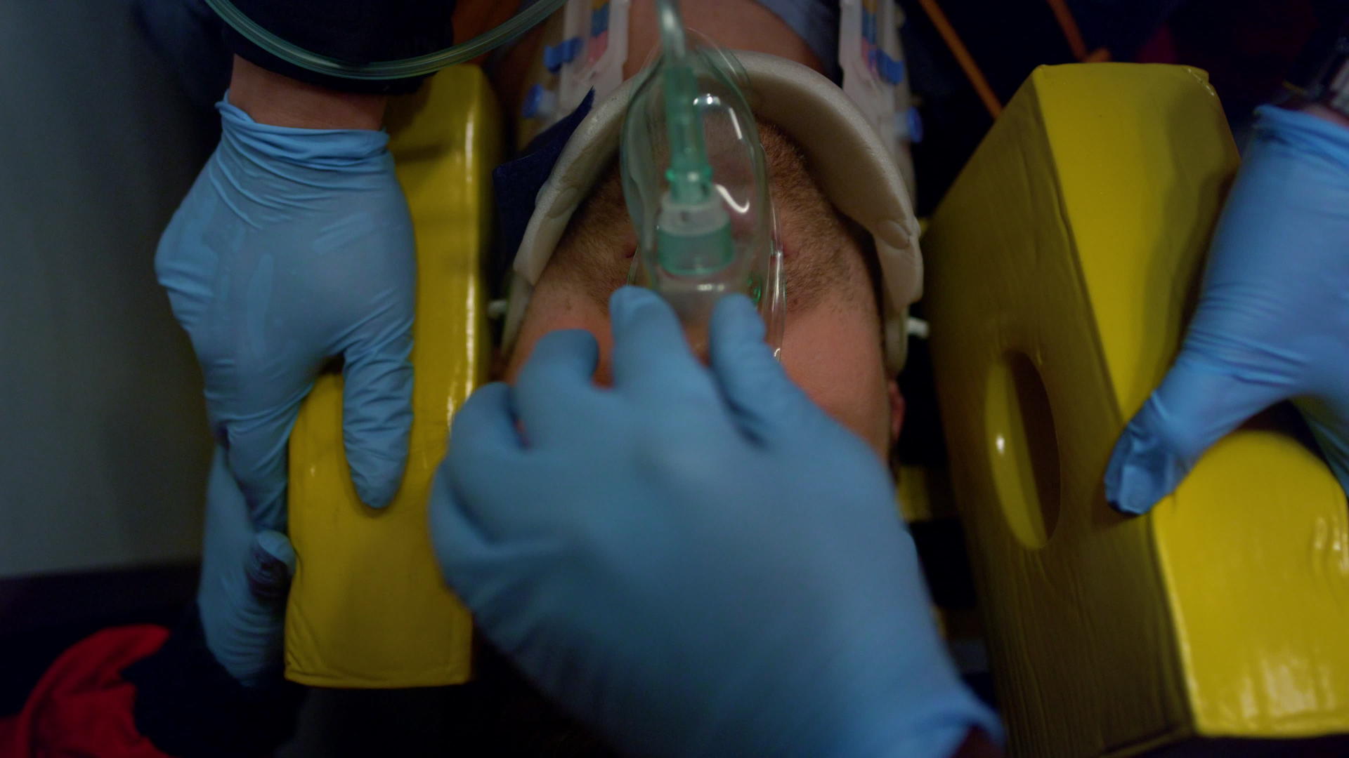 戴手套的辅助医护人员为患者戴上氧气面罩视频的预览图
