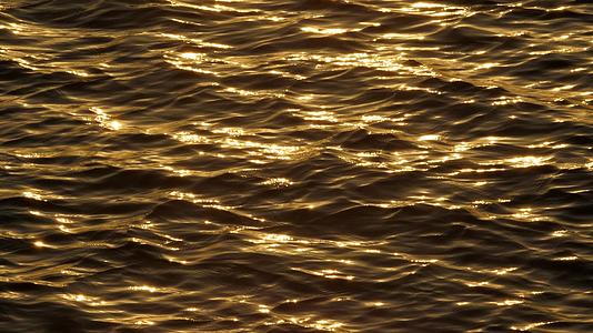 日落时水面的金色反射出美丽的闪光海洋波纹的自然反射4k视频的预览图