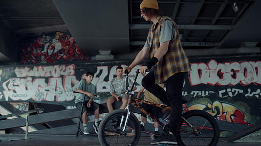 在滑板公园和墙壁上涂鸦的年轻时尚赛车越野自行车视频的预览图