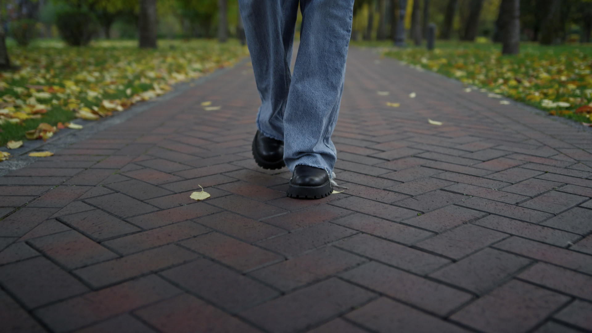 秋天穿着靴子和牛仔裤的女人在公园里散步视频的预览图