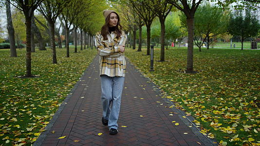 秋天美丽时尚的女孩在公园里散步视频的预览图