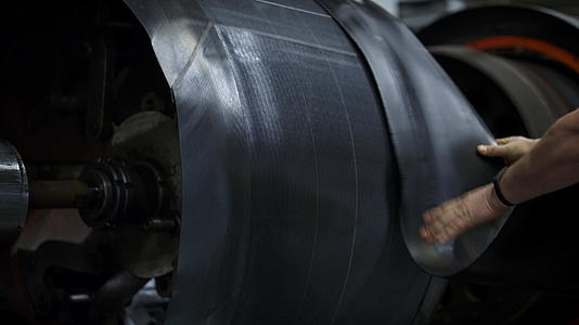 轮胎制造商用手在工业车间机器上设置新的橡胶带视频的预览图