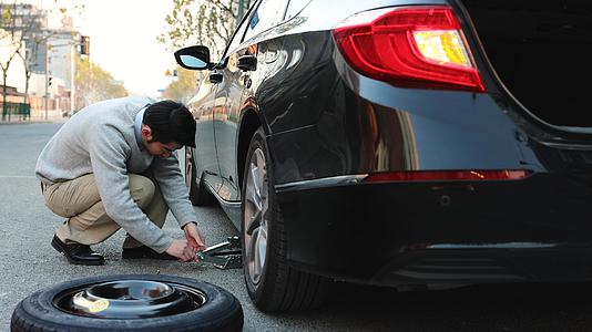 男人在路边使用千斤顶更换汽车备胎视频的预览图