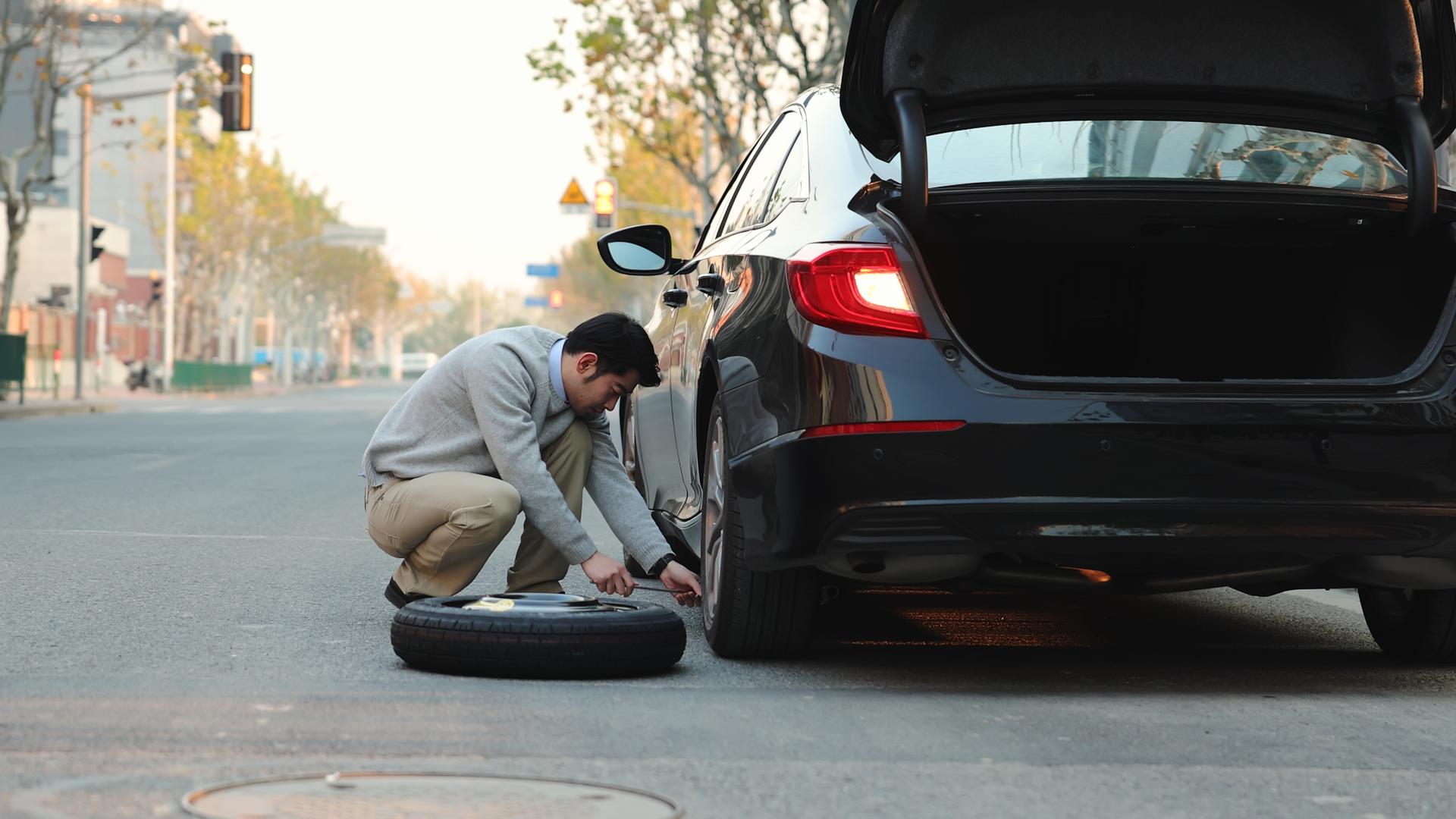 男人在路边使用千斤顶更换汽车备胎视频的预览图