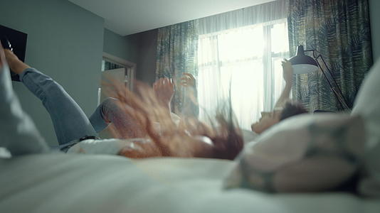 一对漂亮的夫妇摔倒在酒店房间的床上视频的预览图