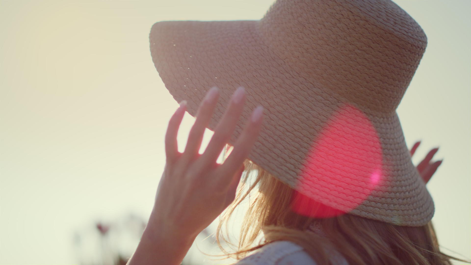 美丽的女人在阳光下戴着草帽视频的预览图