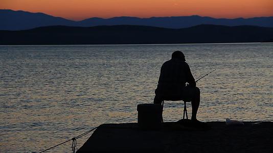 日落前在海边钓鱼的渔夫视频的预览图