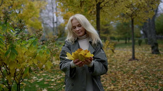 美丽的老太太走在秋天的公园里视频的预览图