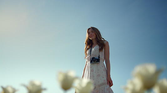 青年女性围绕蓝天背景旋转享受白花视频的预览图