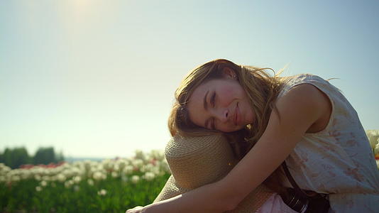 一个在阳光明媚的日子里微笑的女孩坐在公园里视频的预览图