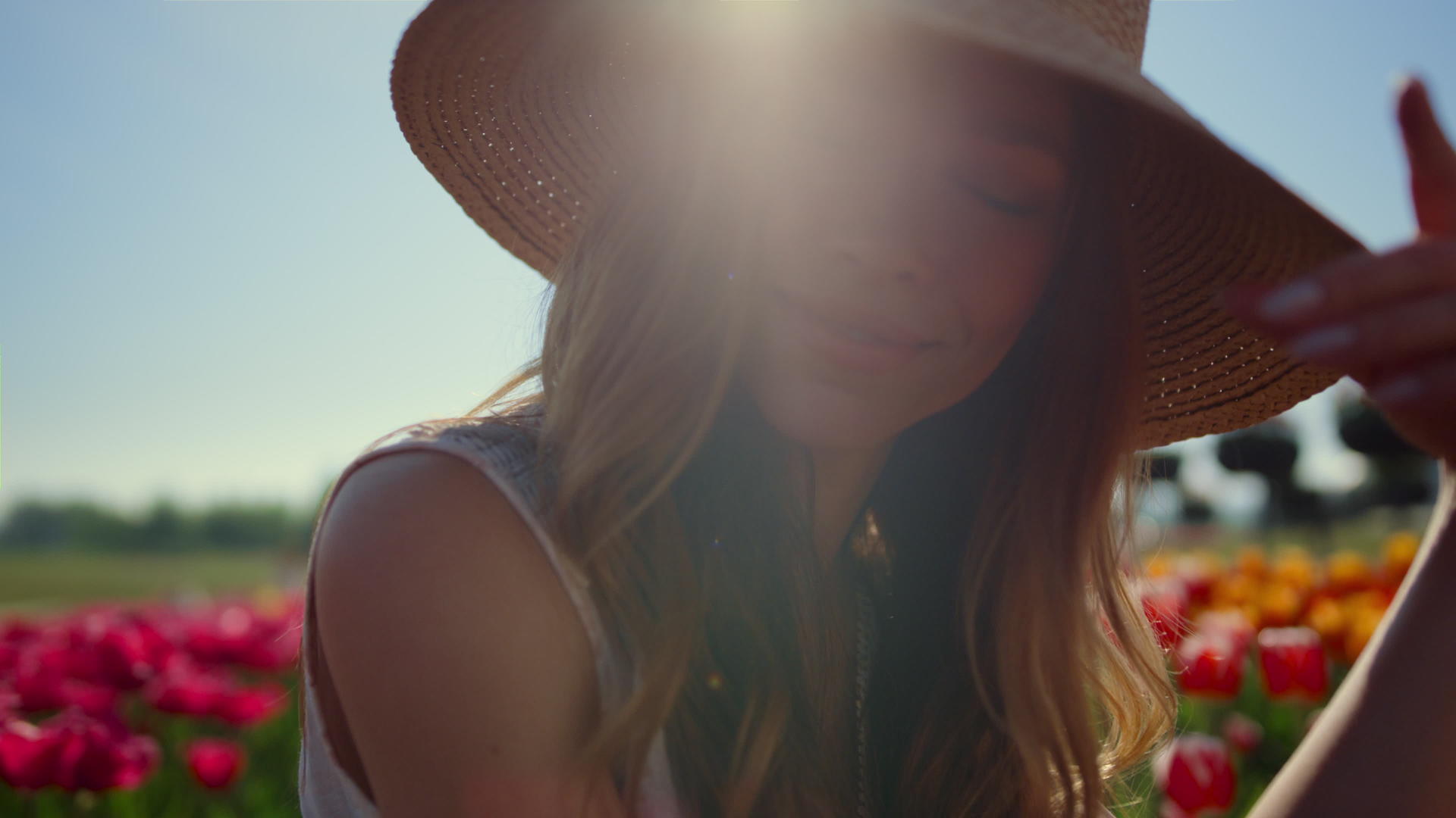 在花卉背景的阳光下美丽的女人肖像脱下草帽视频的预览图