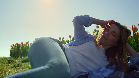 一个放松的女人躺在郁金香花园里视频的预览图