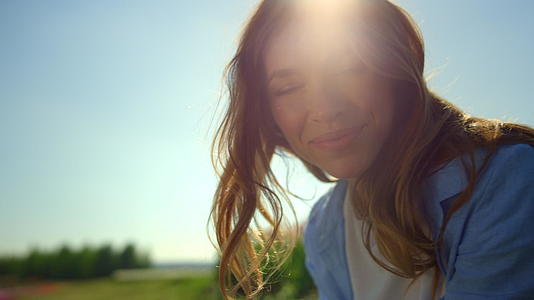 快乐女人的肖像在柔和的日落光线下在夏日花卉背景中微笑视频的预览图