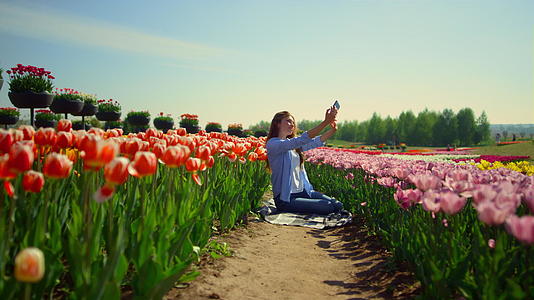明亮的郁金香田和年轻女性在花卉背景中自拍视频的预览图