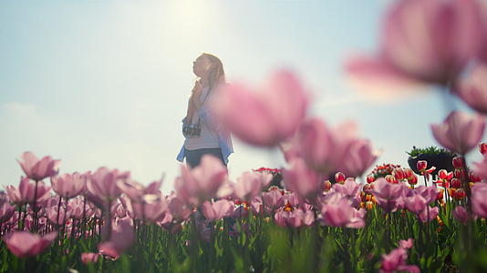 年轻女子穿着休闲服站在阳光下的花园里视频的预览图