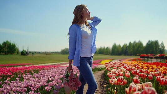 轻松的女人拿着花篮站在郁金香美丽的花田里视频的预览图