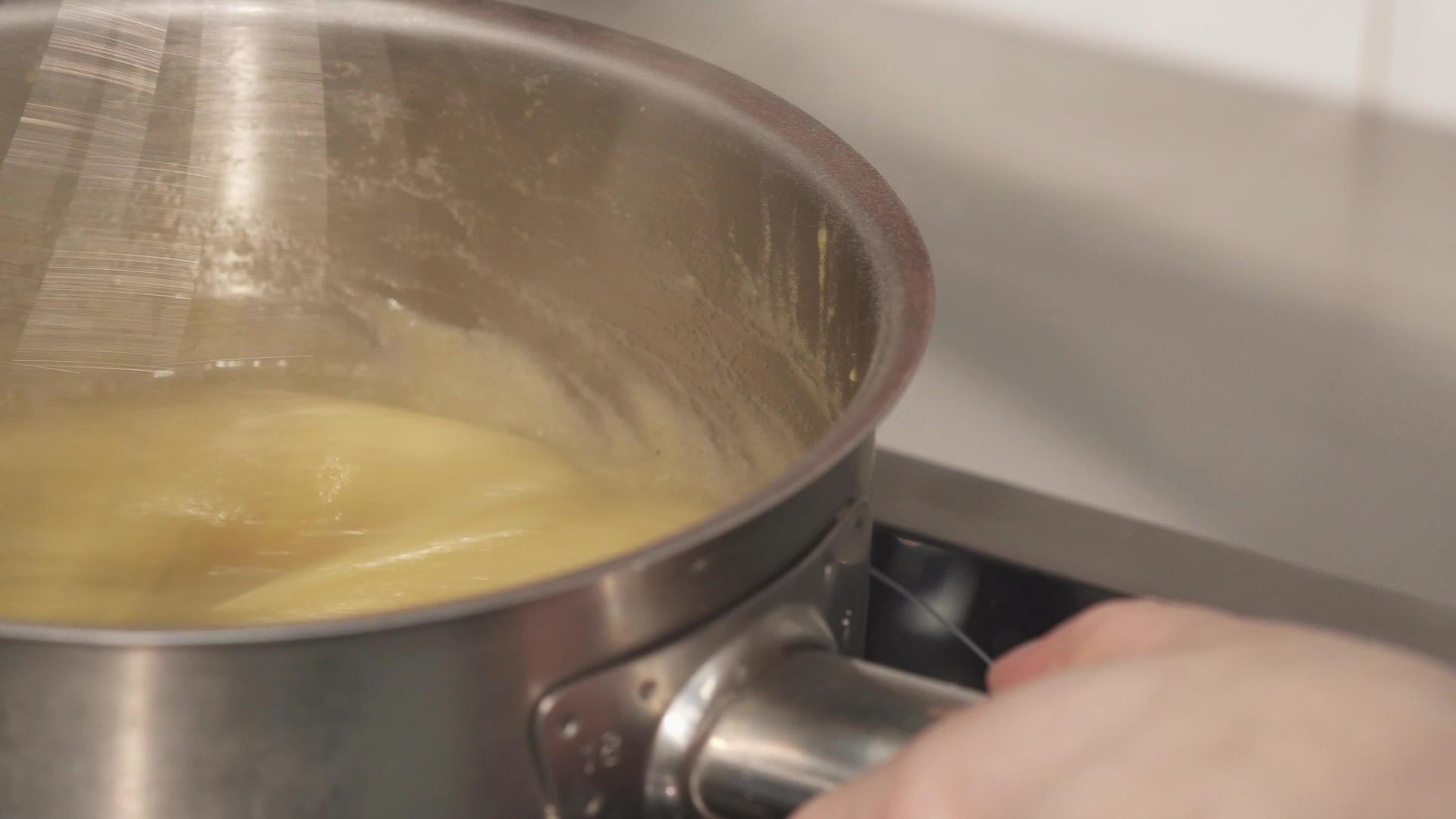 近镜头专业厨师在碗里加热奶油视频的预览图