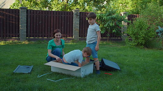 快乐的家庭在草地上玩送货箱慢动作稳态射击Stadicam视频的预览图