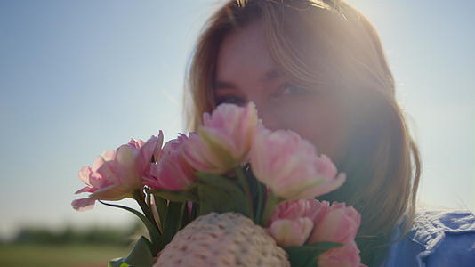 在阳光的反射下美丽的女人闻到了温柔的花束视频的预览图