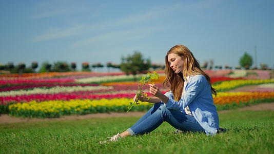 夏天美丽的女孩坐在草地上视频的预览图