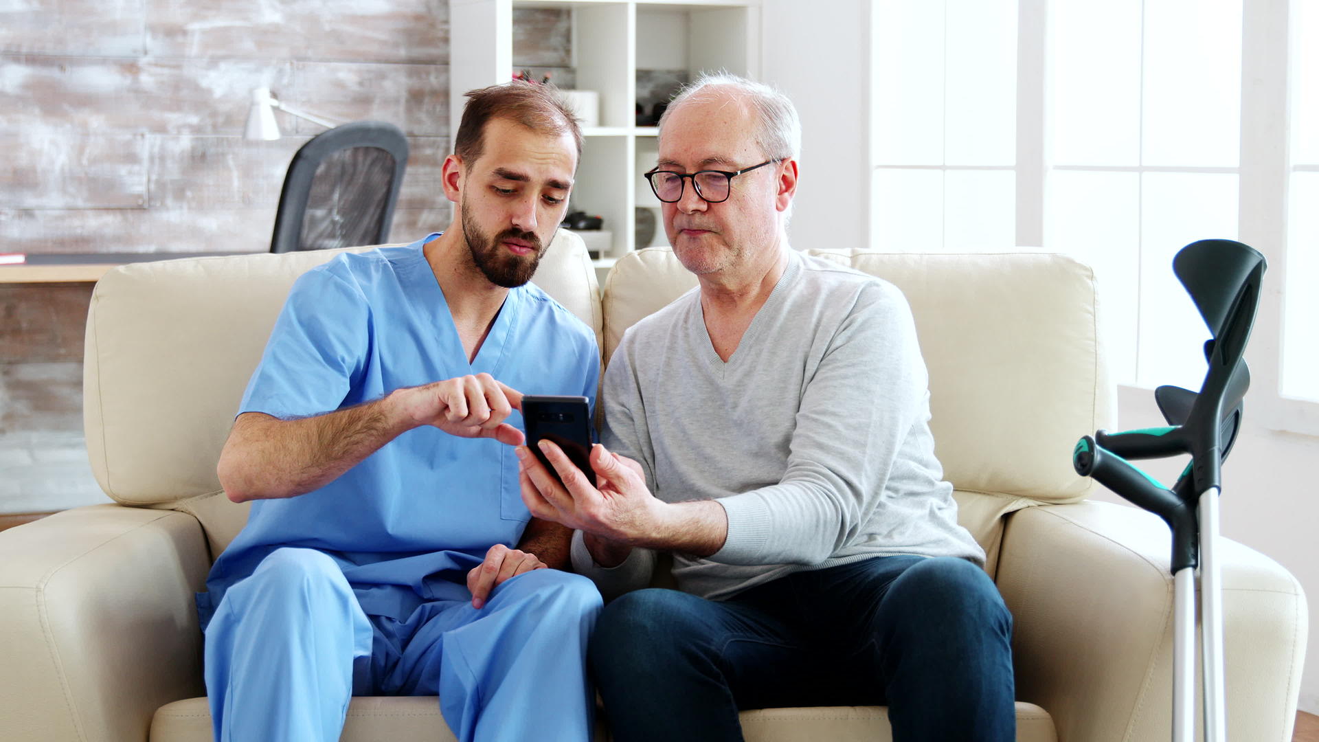 男护士帮助退休老人使用智能手机视频的预览图