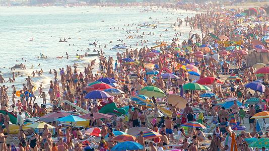 在炎热的夏天海滩上到处都是人和太阳伞视频的预览图