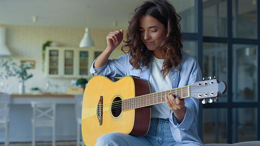 女孩在家弹吉他快乐的女士在弦器上练习音视频的预览图