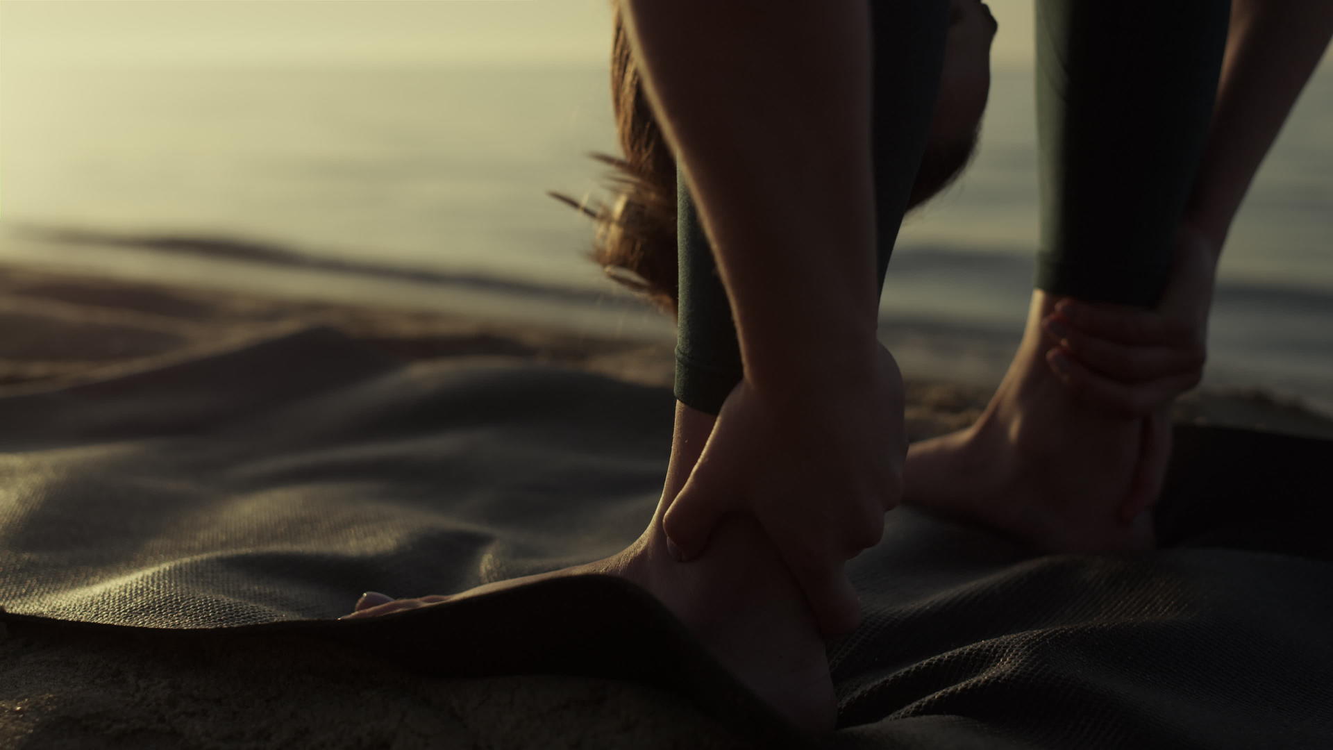 在沙滩特写镜头上灵活的女运动员弯曲身体到脚视频的预览图
